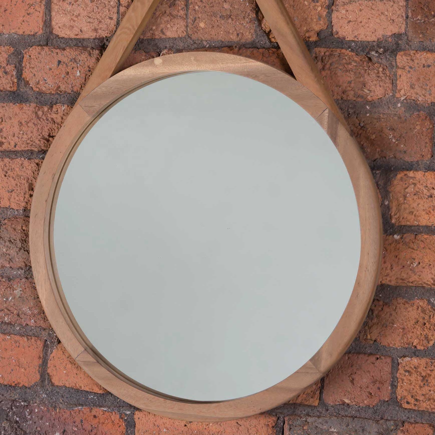 Round mirror with a light-colored, natural wood frame and triangular hanging detail.