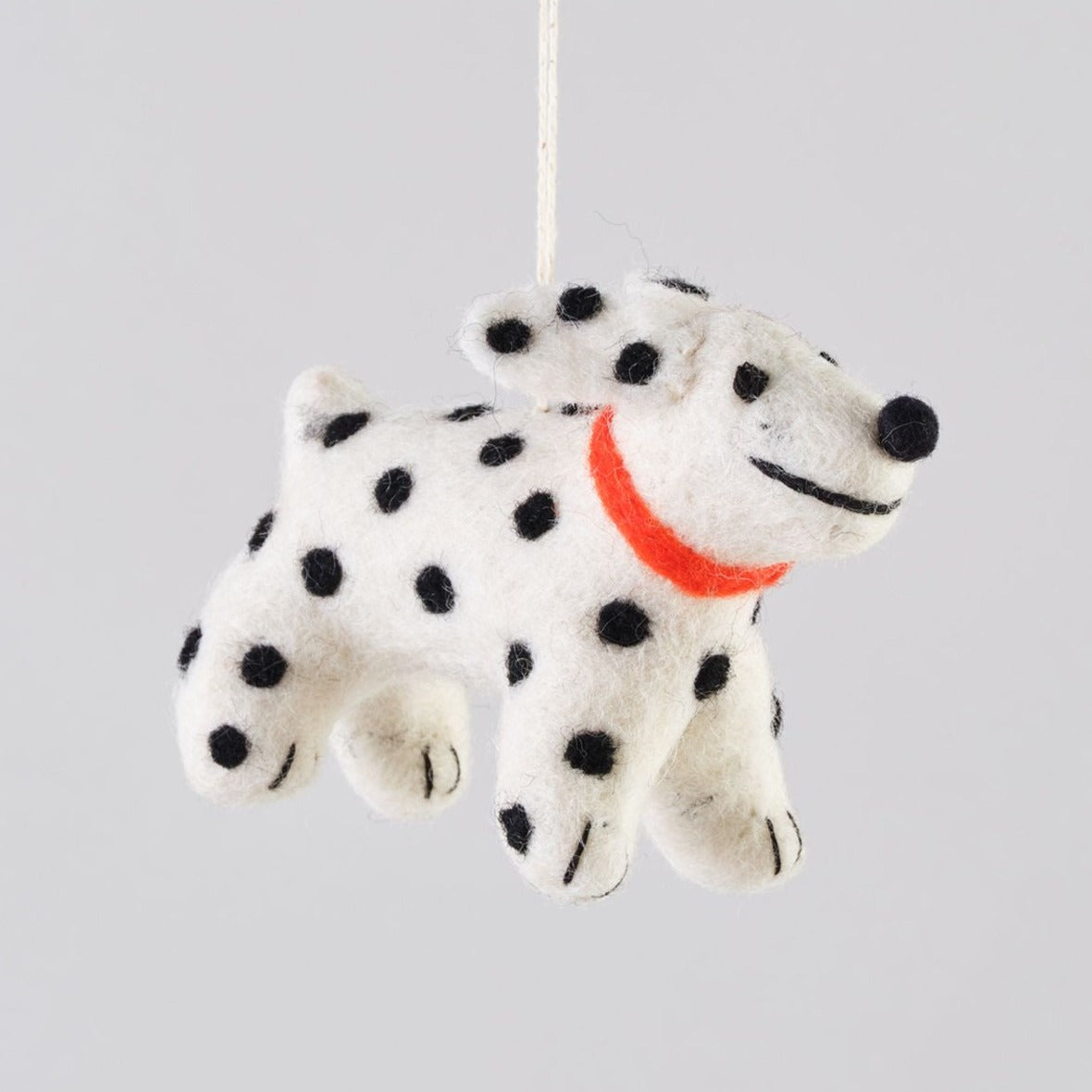 Felt Dalmatian dog ornament with black spots and an orange collar, hanging from a string.