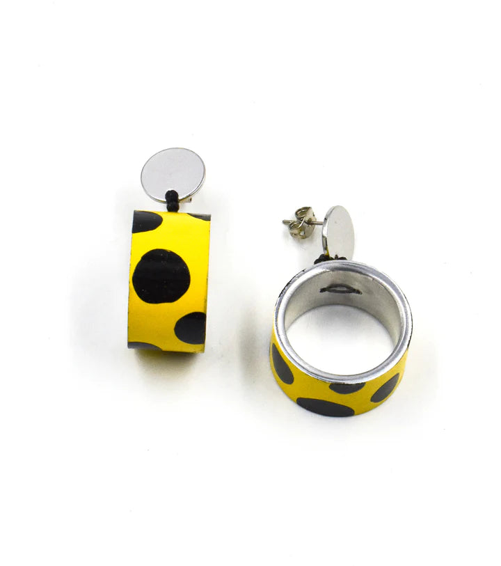 A pair of yellow and black polka dot earrings, showing both the front rectangular drop with a silver disc and the side profile of the matching silver hoop earring.