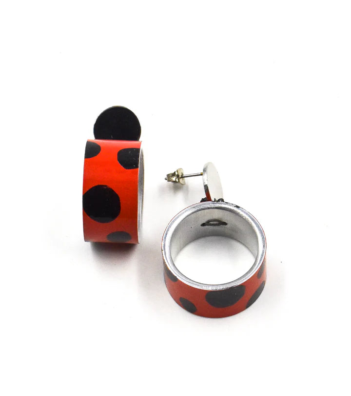 A pair of red and black ladybug-patterned ring earrings, with one earring standing upright to show the back post and the other lying flat to show the front face, on a white background.