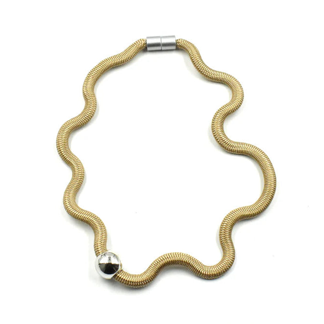 A gold-toned snake chain necklace with a wavy, scalloped edge and a polished silver ball accent on one side, displayed on a clean white background.