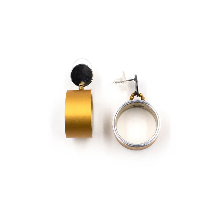 A pair of gold and silver geometric dangle earrings on a plain white background, one showing the gold cylindrical drop and the other showing the silver-toned hoop with a gold accent and post.