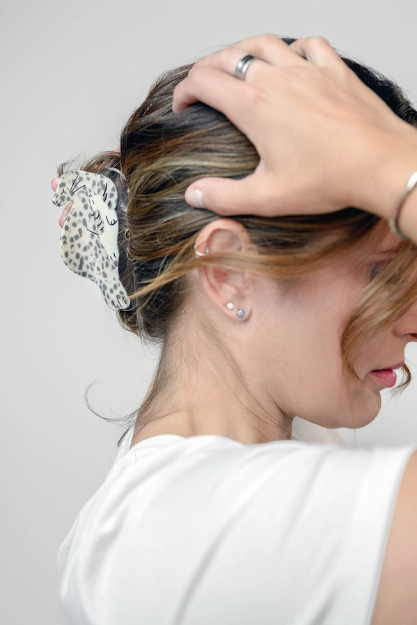 Woman wearing a seal shaped hair clip against a plain background