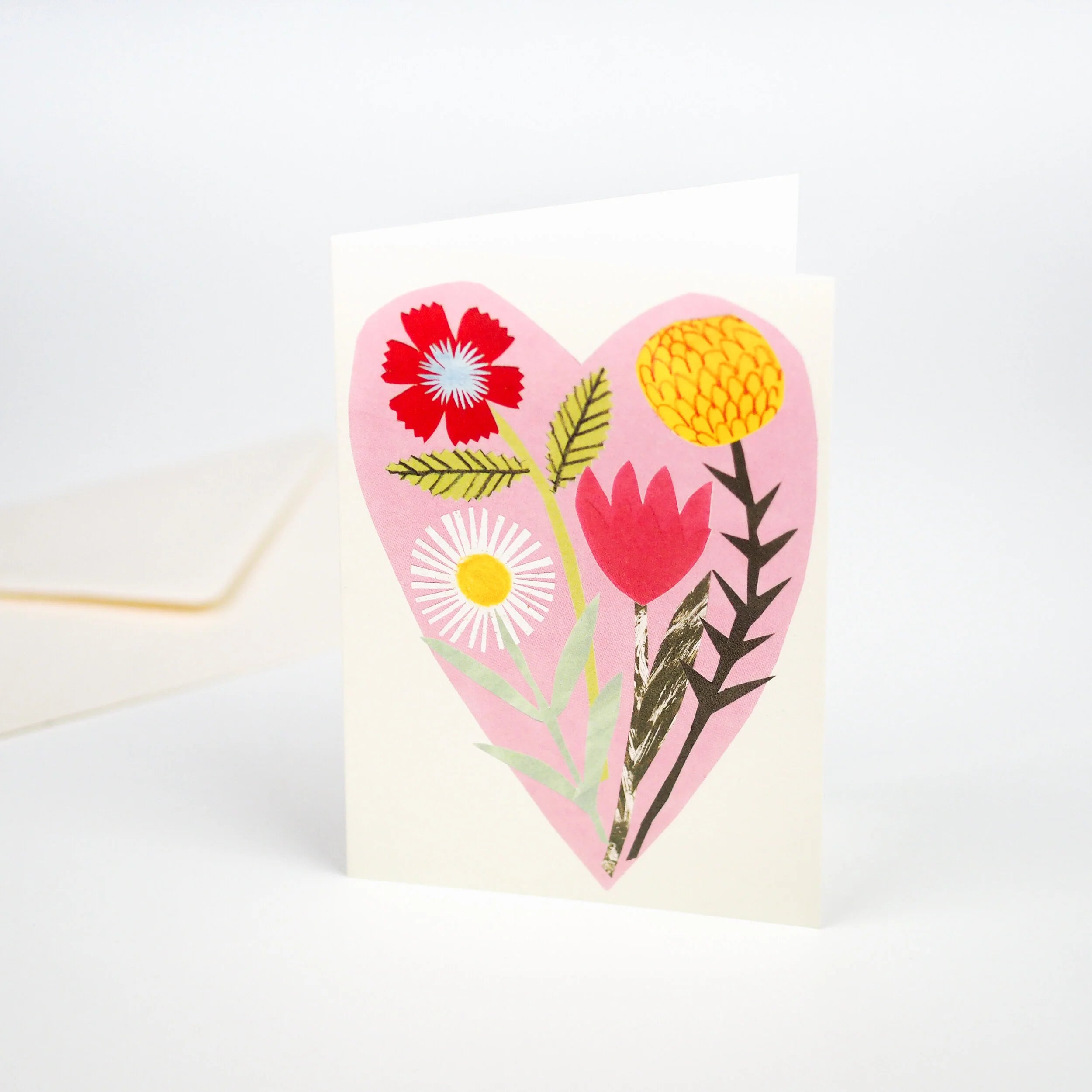 Greeting card featuring a pink heart-shaped design with stylized red, yellow, and white flowers.