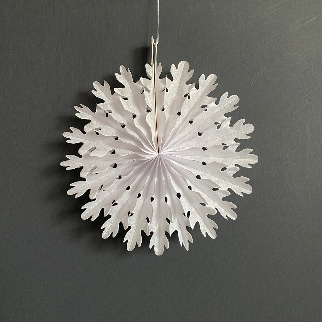 White paper snowflake decoration, hanging, with a lacy, folded design.