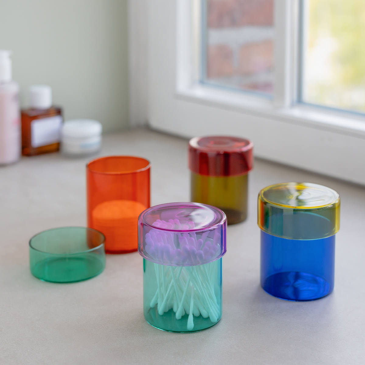 Colorful plastic containers on a surface with a window in the background
