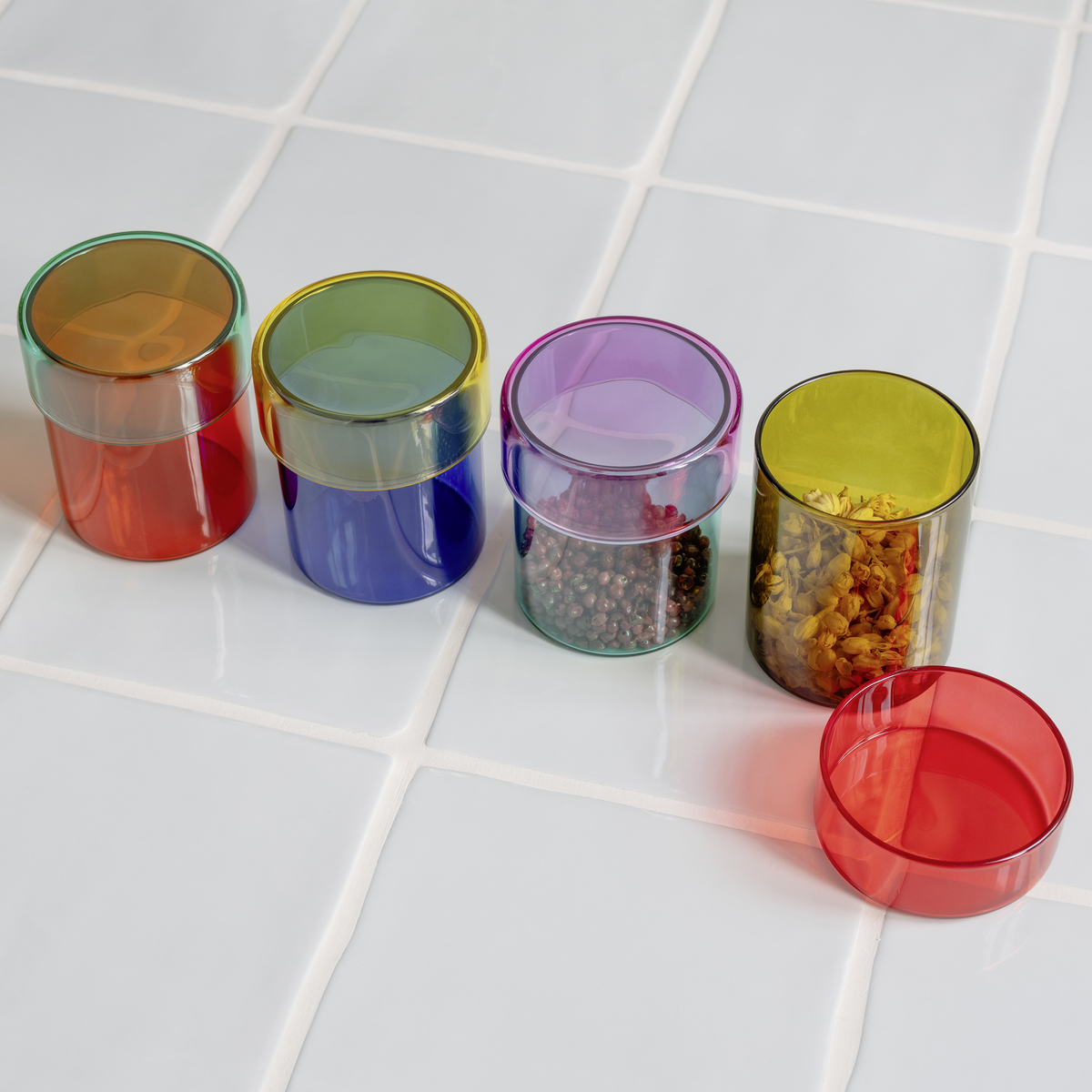 Set of colorful transparent containers with lids on a tiled surface