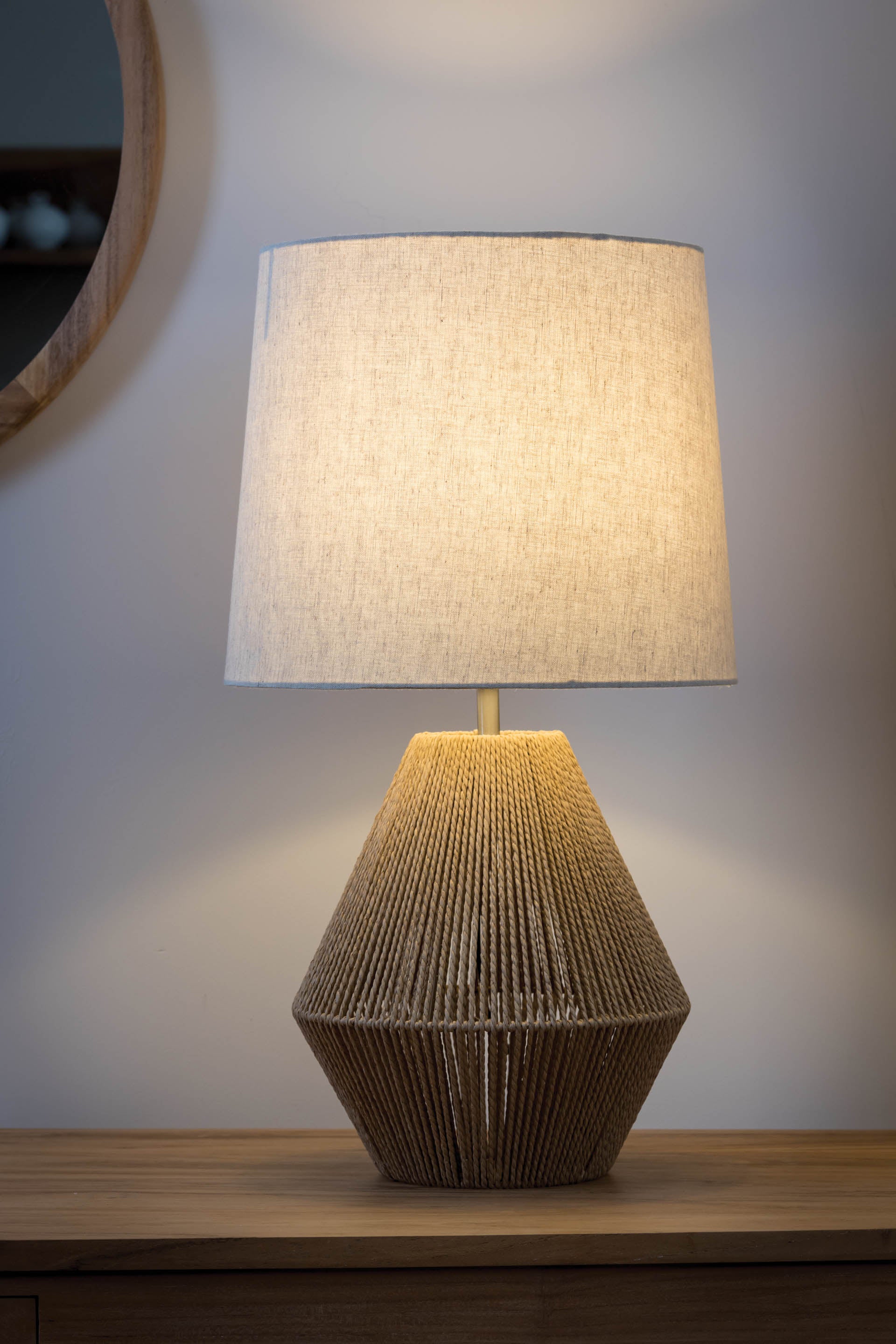 Illuminated table lamp with a beige linen shade and a tan rope base.