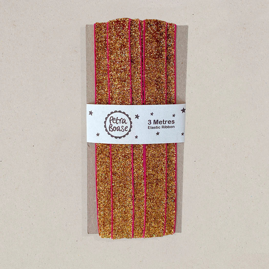 Three meters of gold glitter elastic ribbon with pink edges, packaged on a card.
