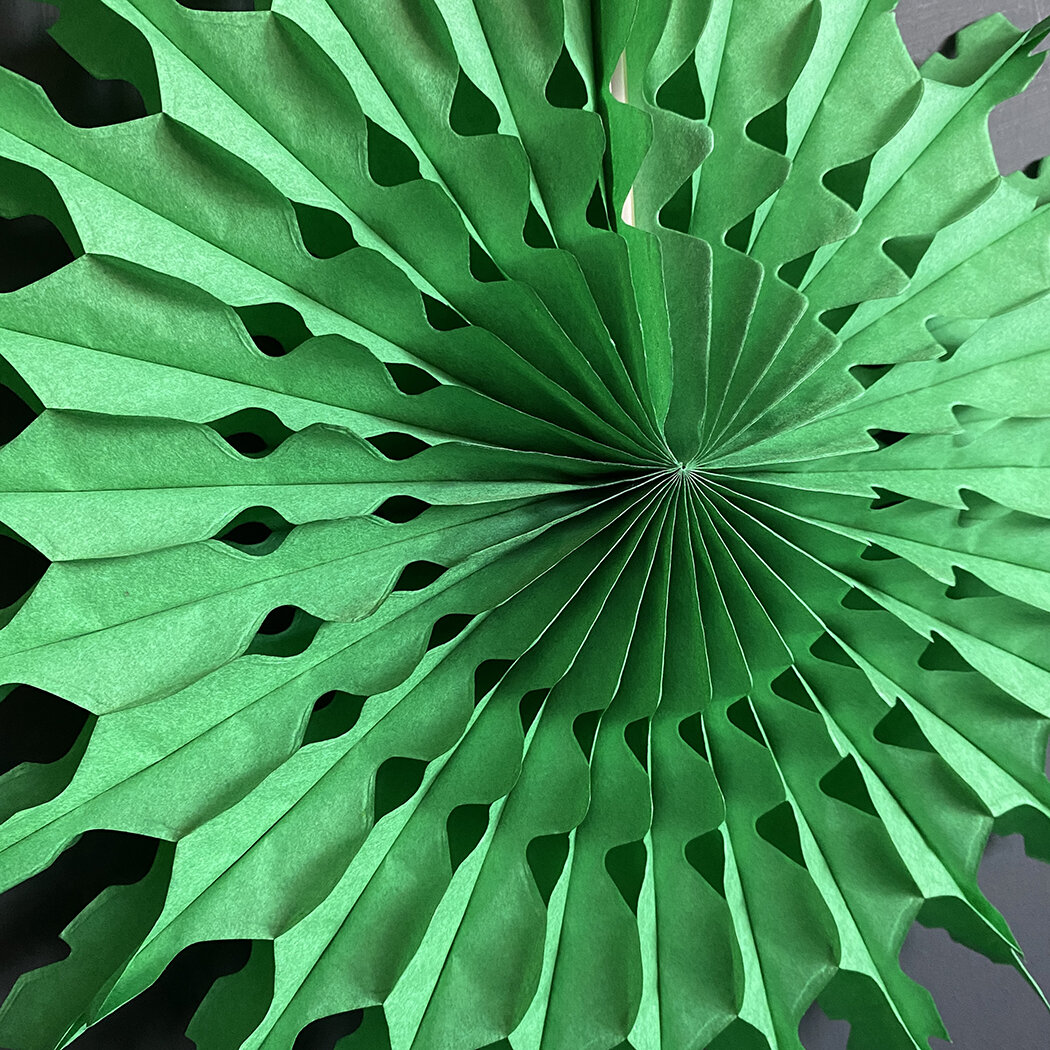 Green paper fan with scalloped edges and cutout details.