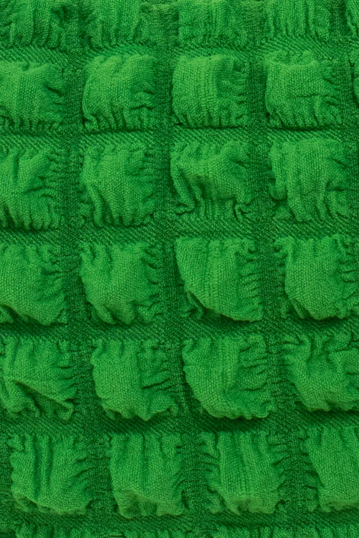 Close-up of bright green textured fabric with a repeating pattern of raised, puffy squares.