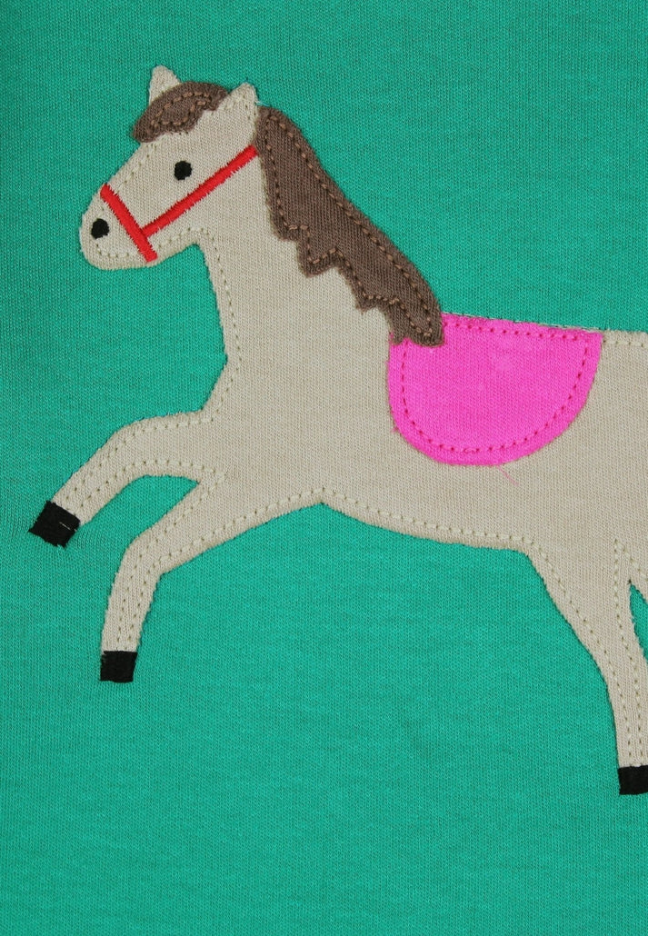 Fabric horse applique with a pink saddle on a teal background