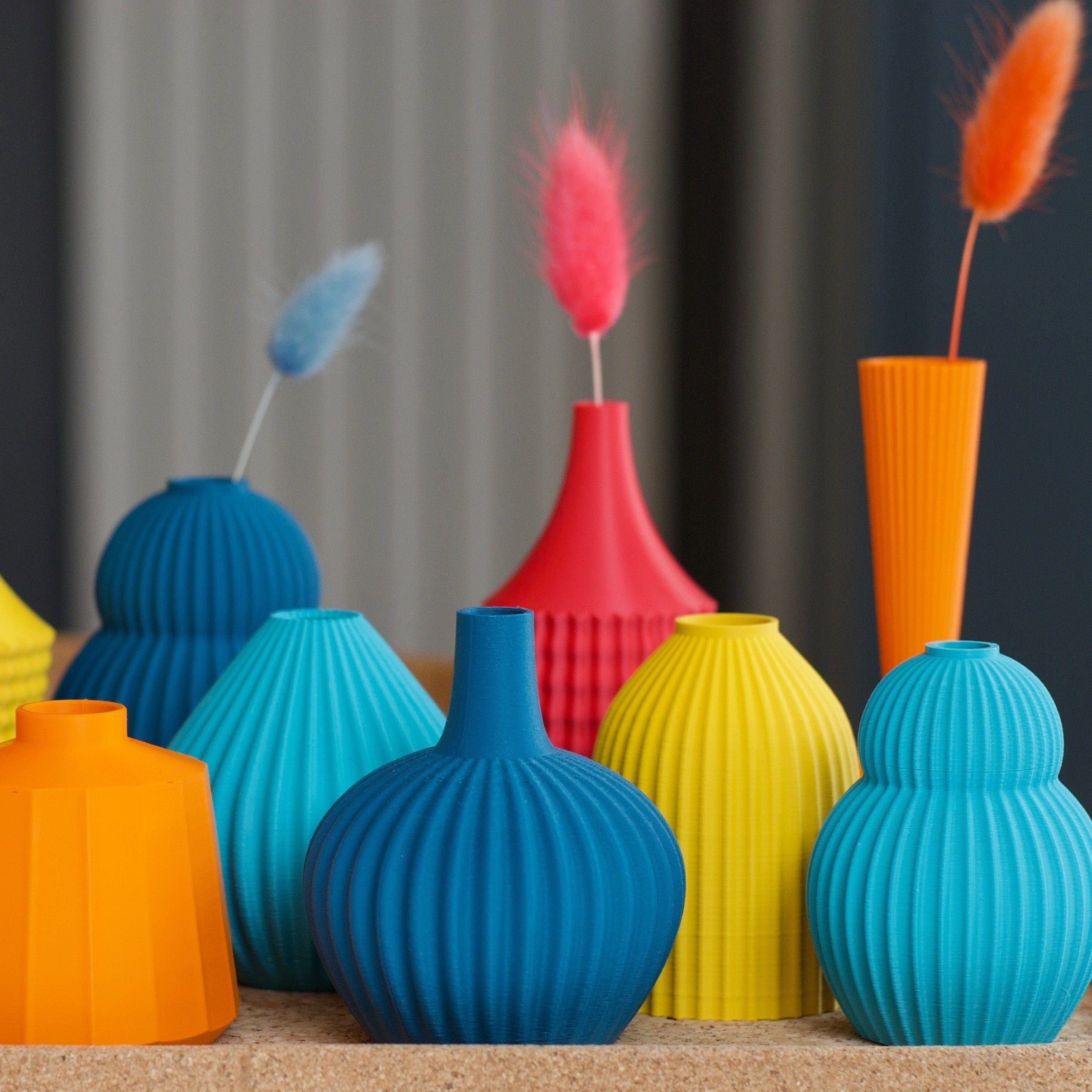 Collection of colorful, vertically ribbed vases in teal, blue, yellow, orange, and red.