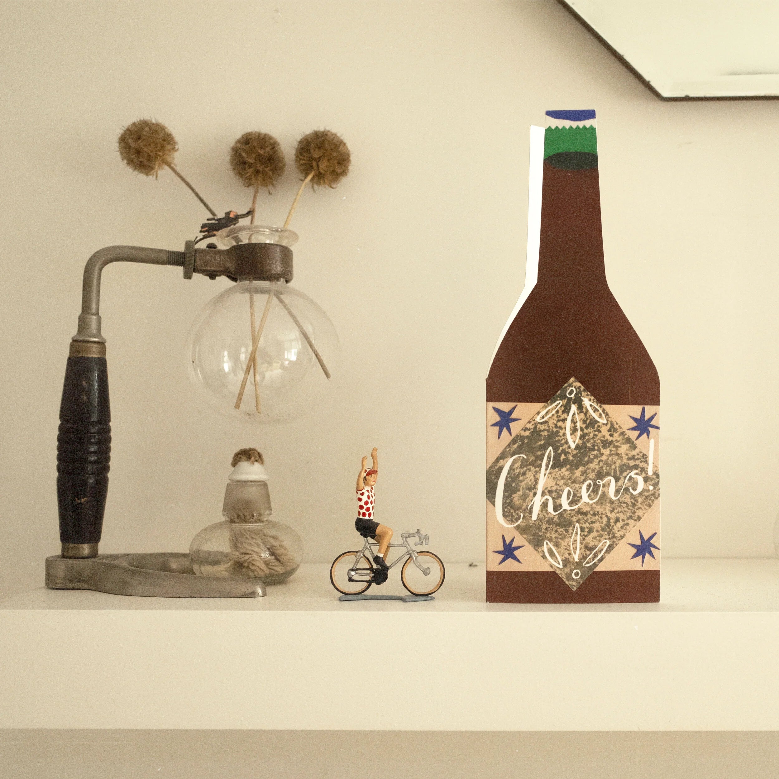 Beer bottle-shaped card with "Cheers!" in calligraphy, blue stars, and a textured brown background.