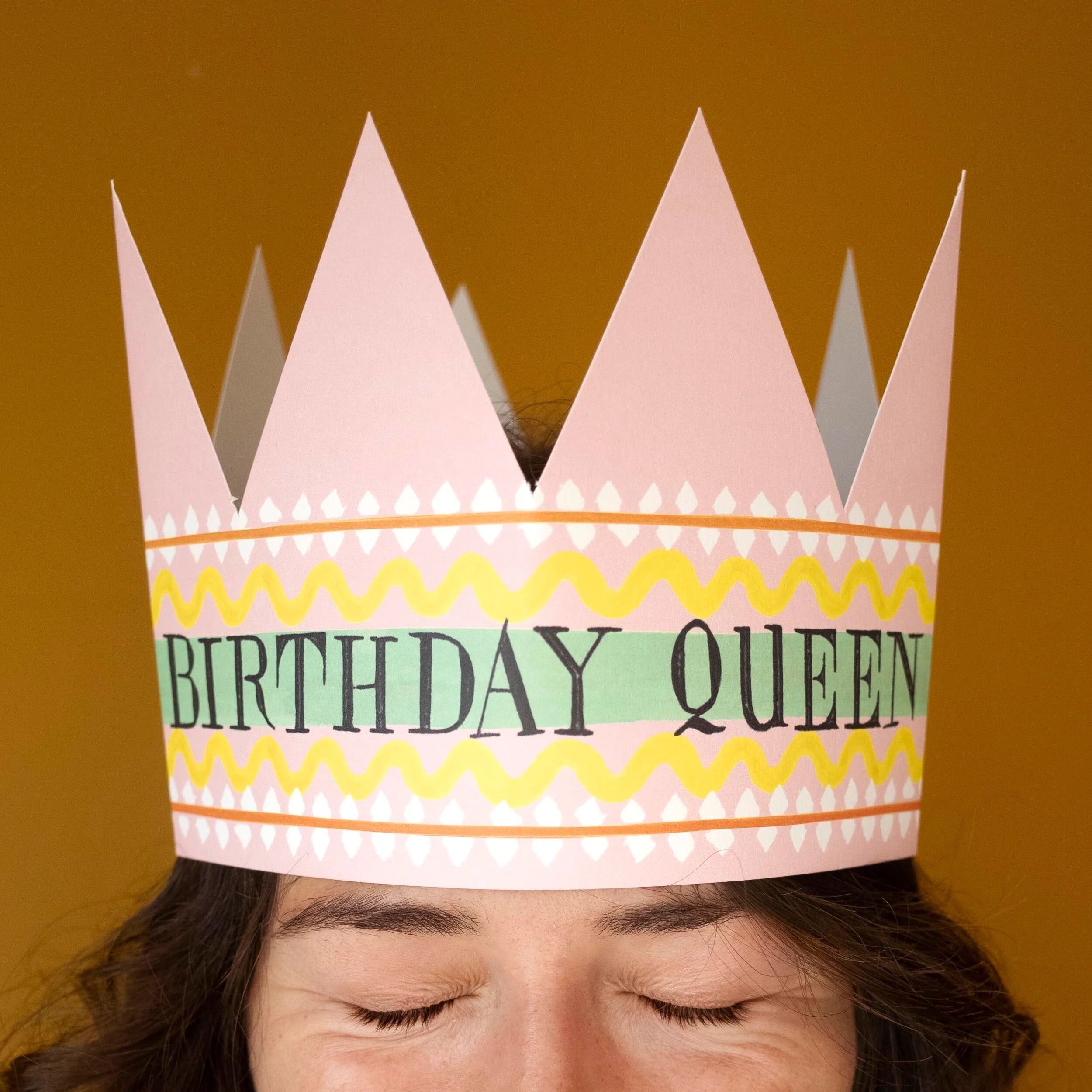 Pink paper crown with "Birthday Queen" in black lettering on a mint green band.