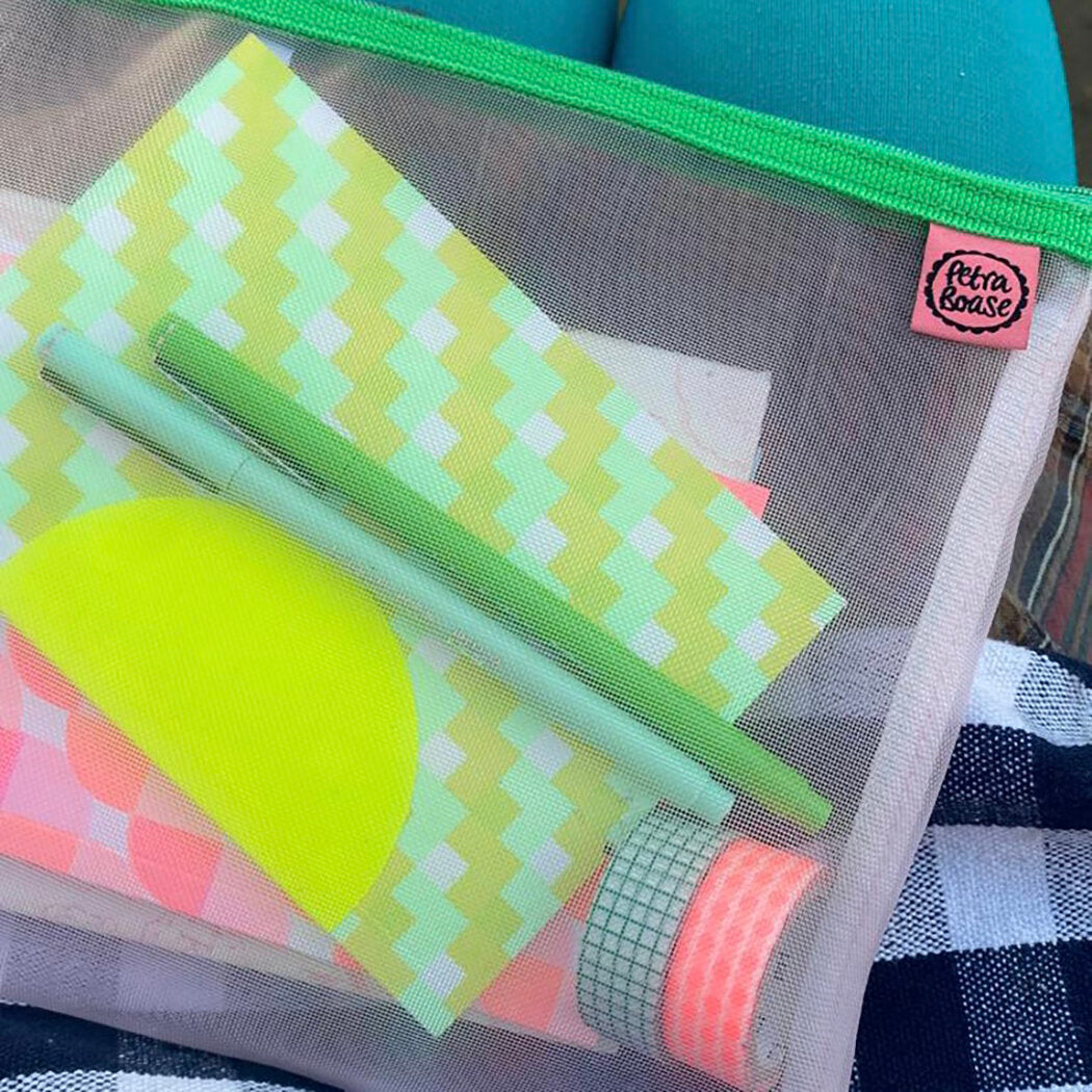Mesh pouch with lime green and pastel yellow stationery, including pens and washi tape.