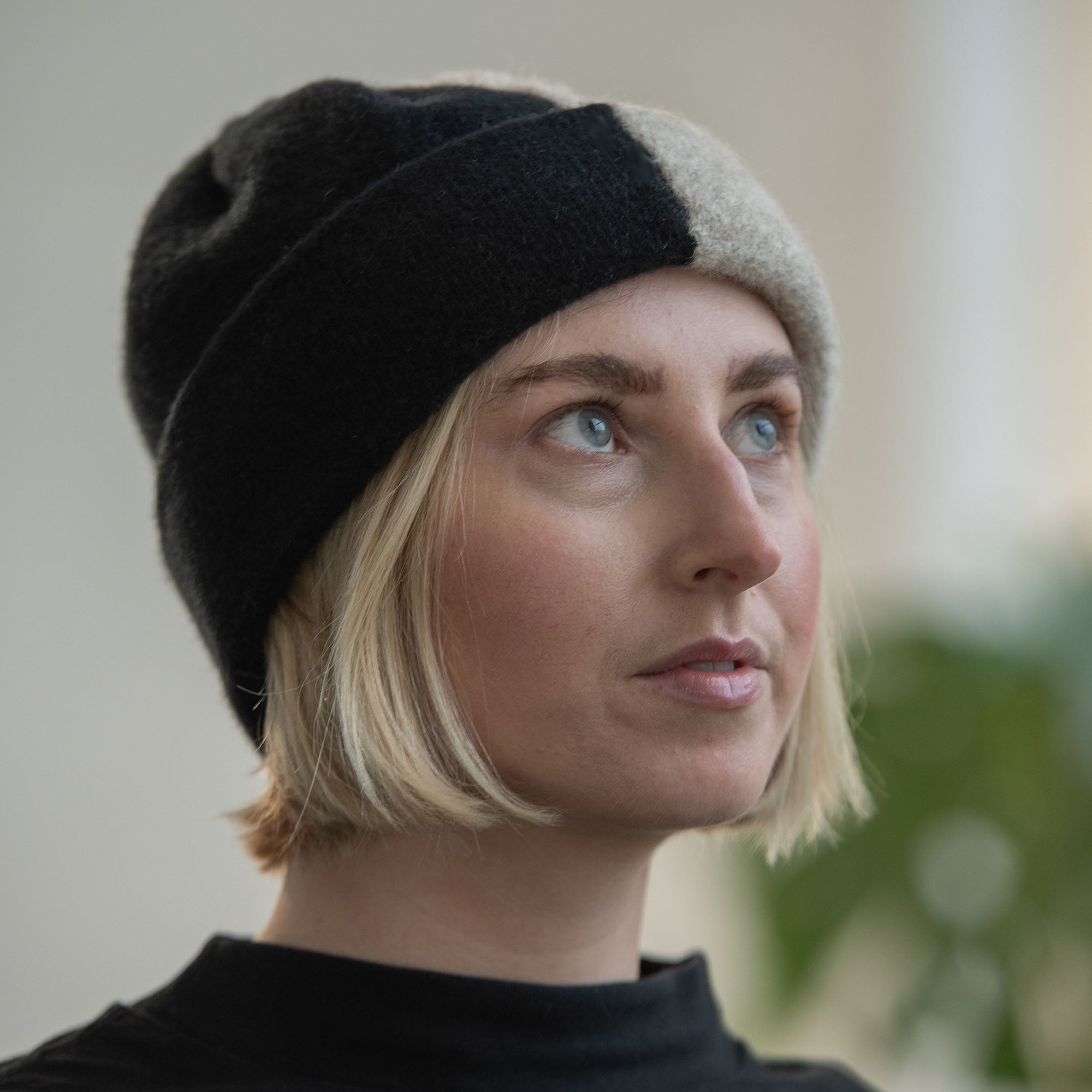 Close-up of a woman wearing a black and beige wool beanie.