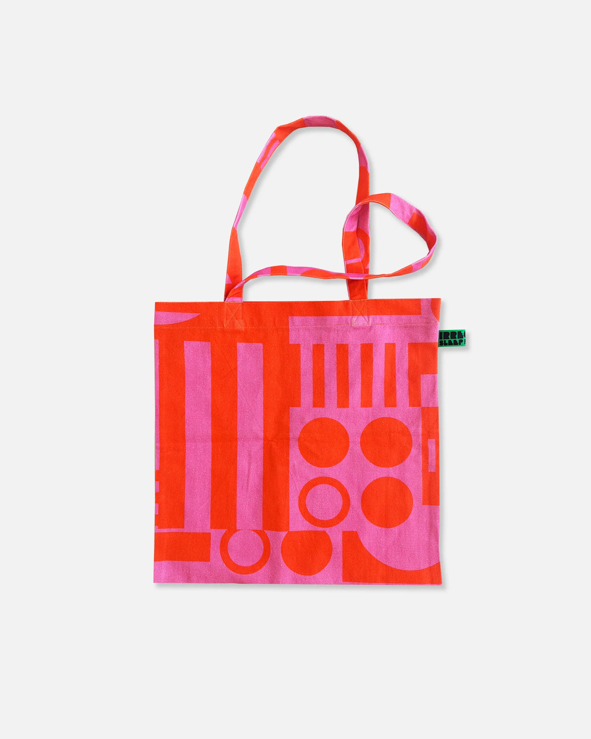 A canvas tote bag featuring a bold abstract geometric pattern in hot pink and bright orange-red, with matching patterned shoulder straps, shown against a plain light gray background.
