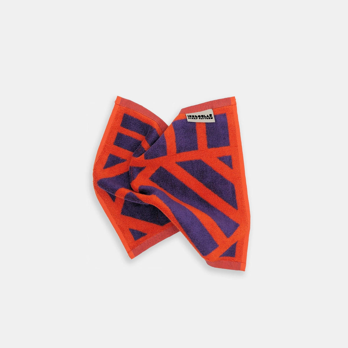 A folded square scarf featuring a bold geometric pattern of bright orange and dark purple stripes, with a small white brand label reading 'maxwell' on one corner, set against a plain light gray background.