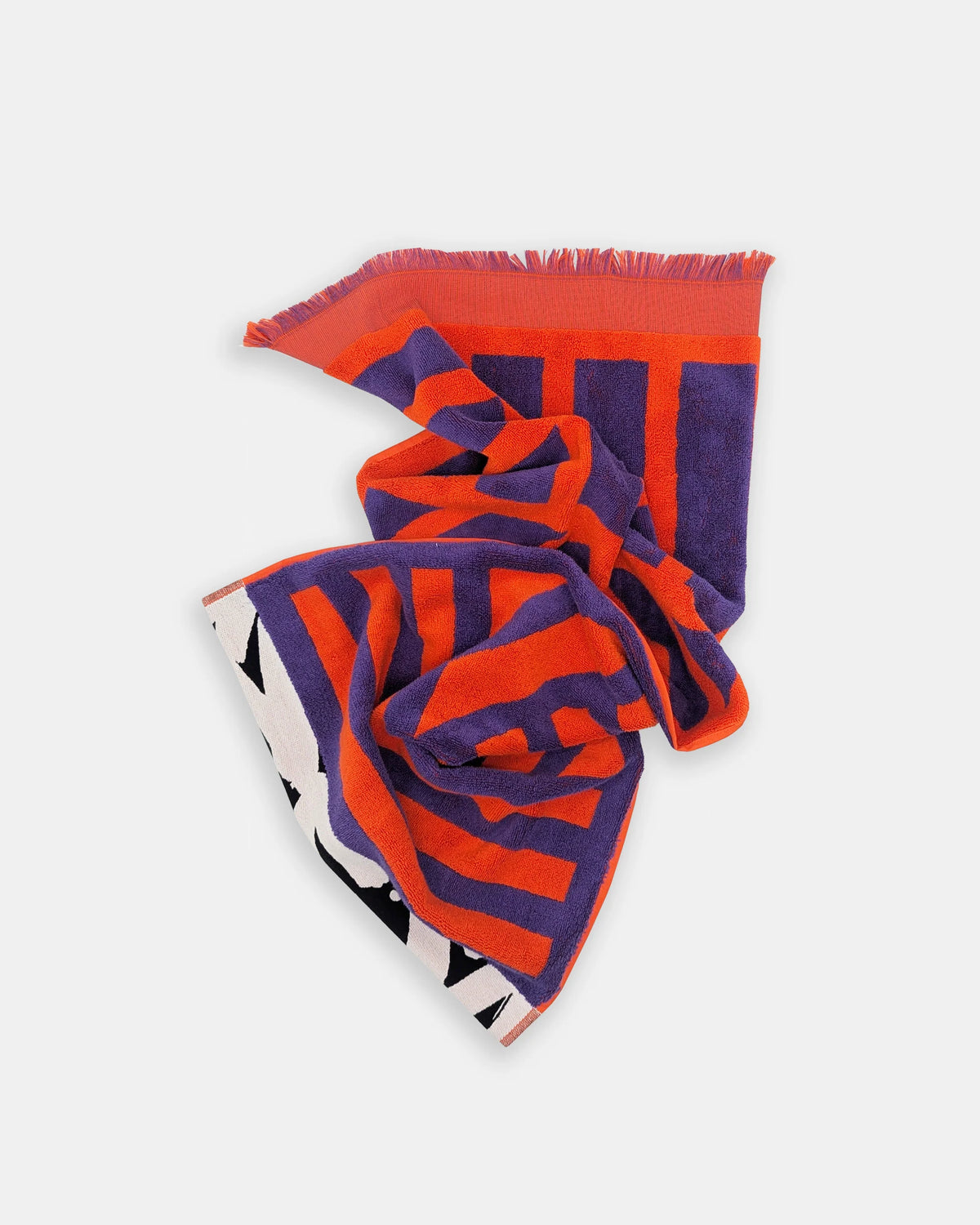 A folded patterned scarf with fringed edges, featuring bold orange and purple stripes with a white, black, and purple geometric pattern on one side, displayed on a light gray background.