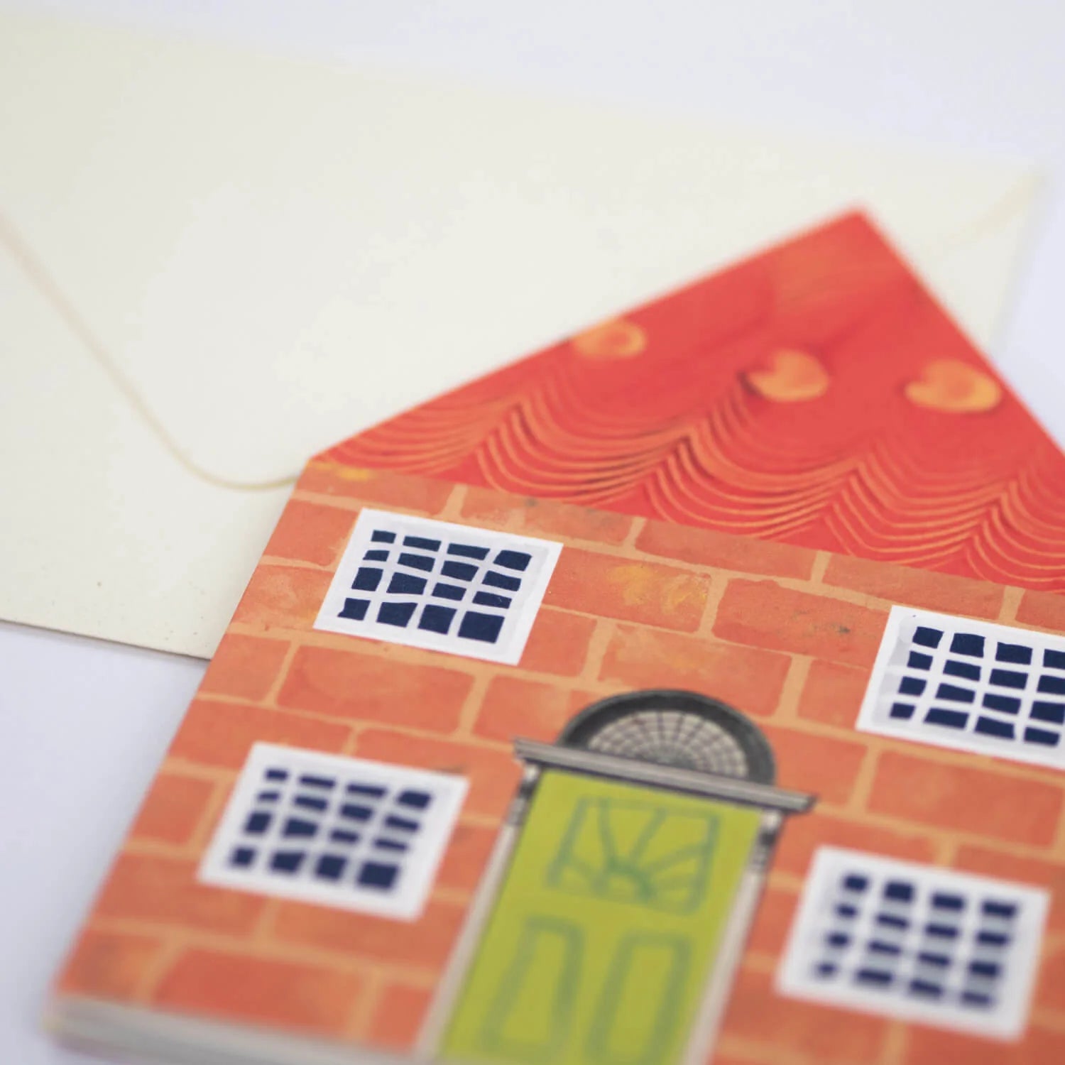 Illustrated house-shaped card with orange brick facade, green door, and multiple small paned windows.