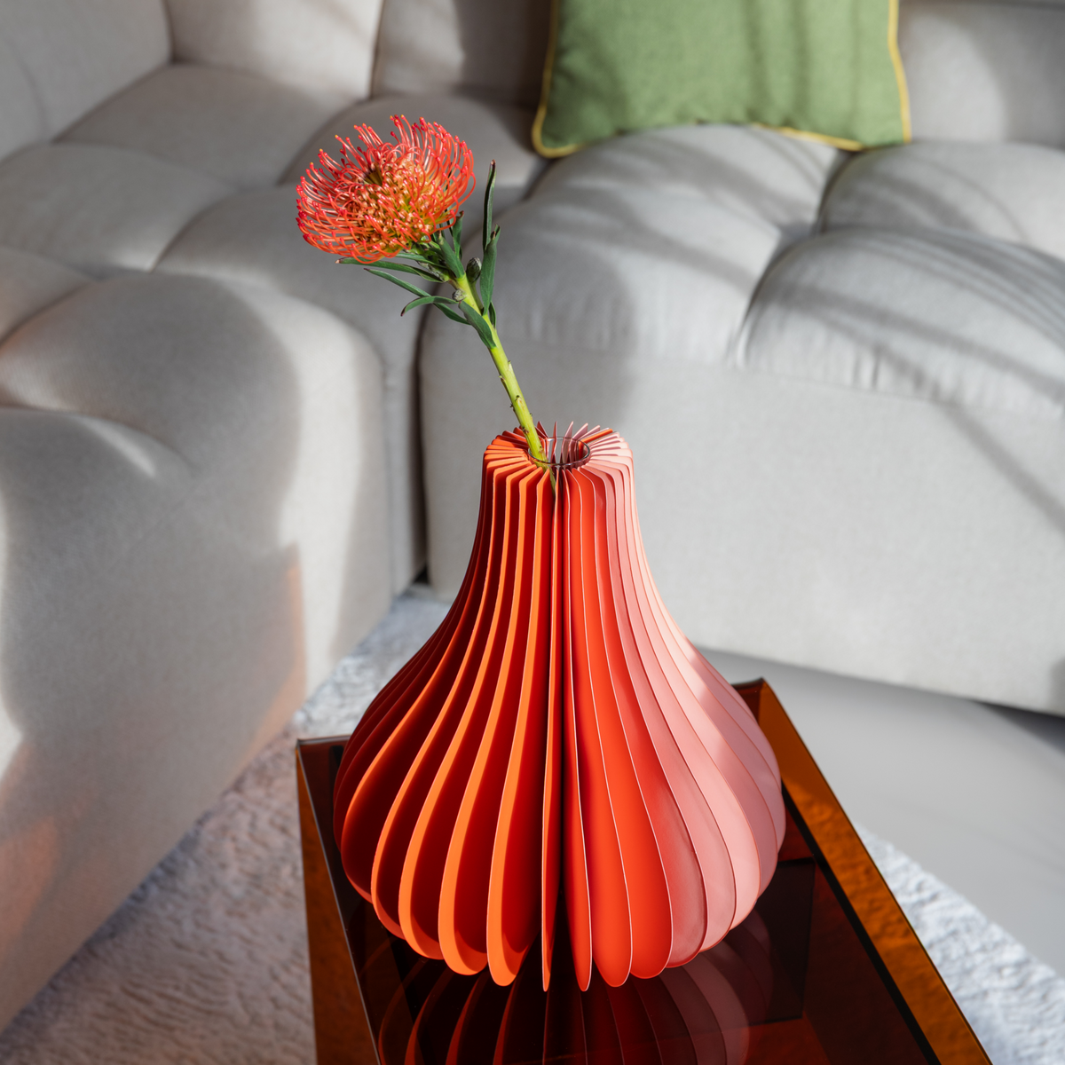 Foldable paper vase with a flower on a wooden table in a living room setting.