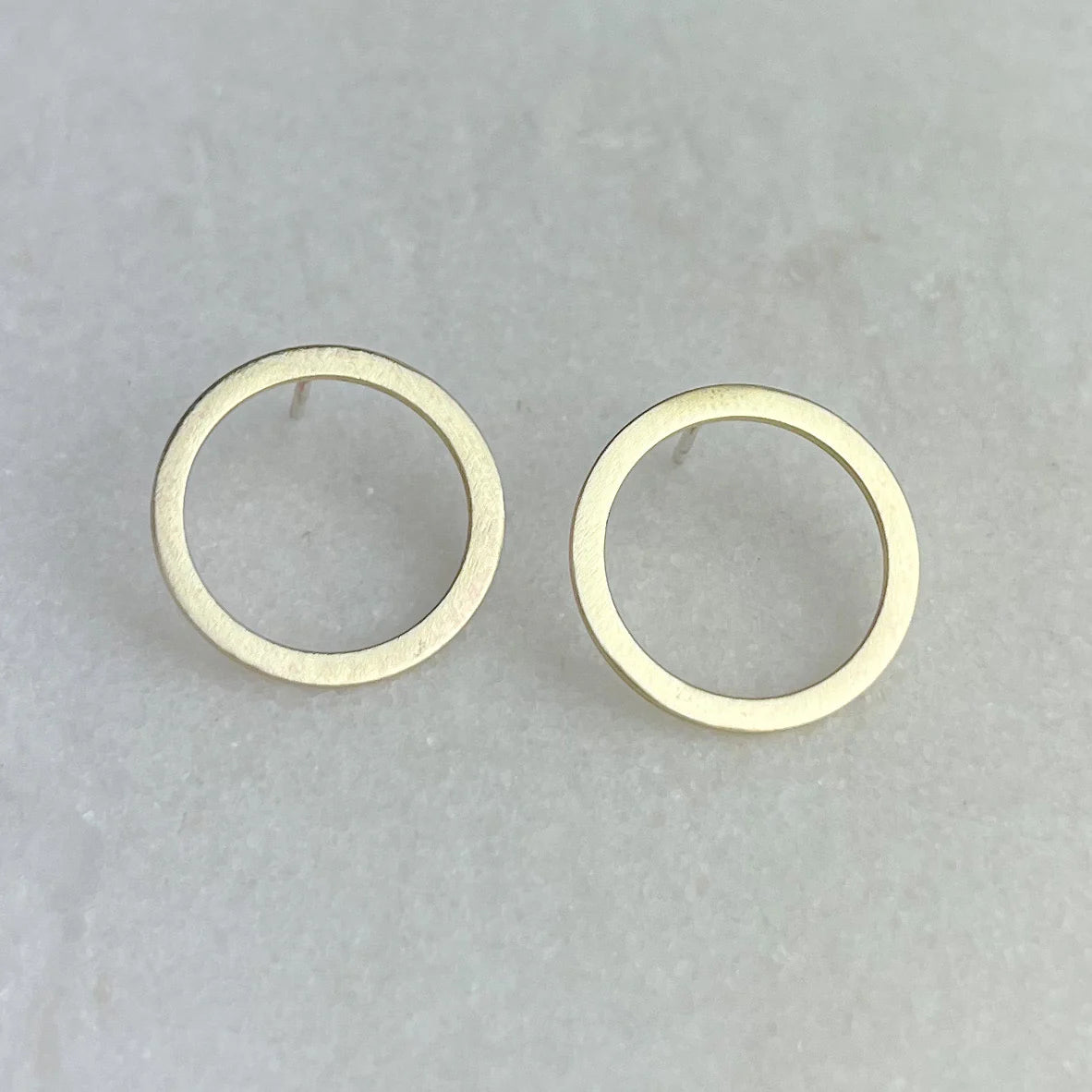 Pair of gold circle stud earrings with a brushed matte finish.