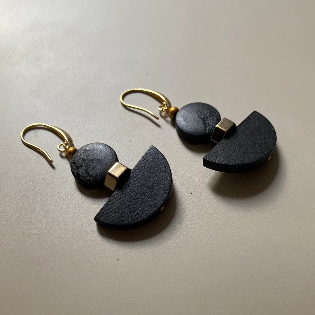 Black and gold earrings on a beige background