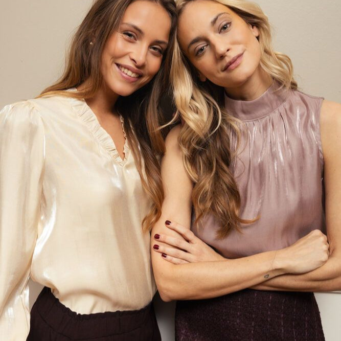 Two women posing together against a plain background