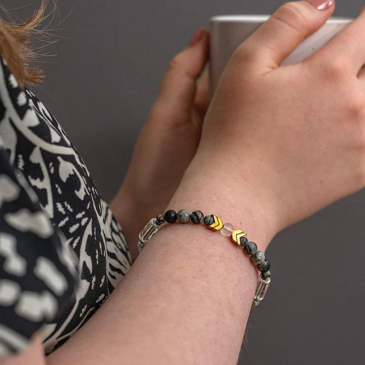 Person wearing a beaded bracelet with geometric patterns on a dark background