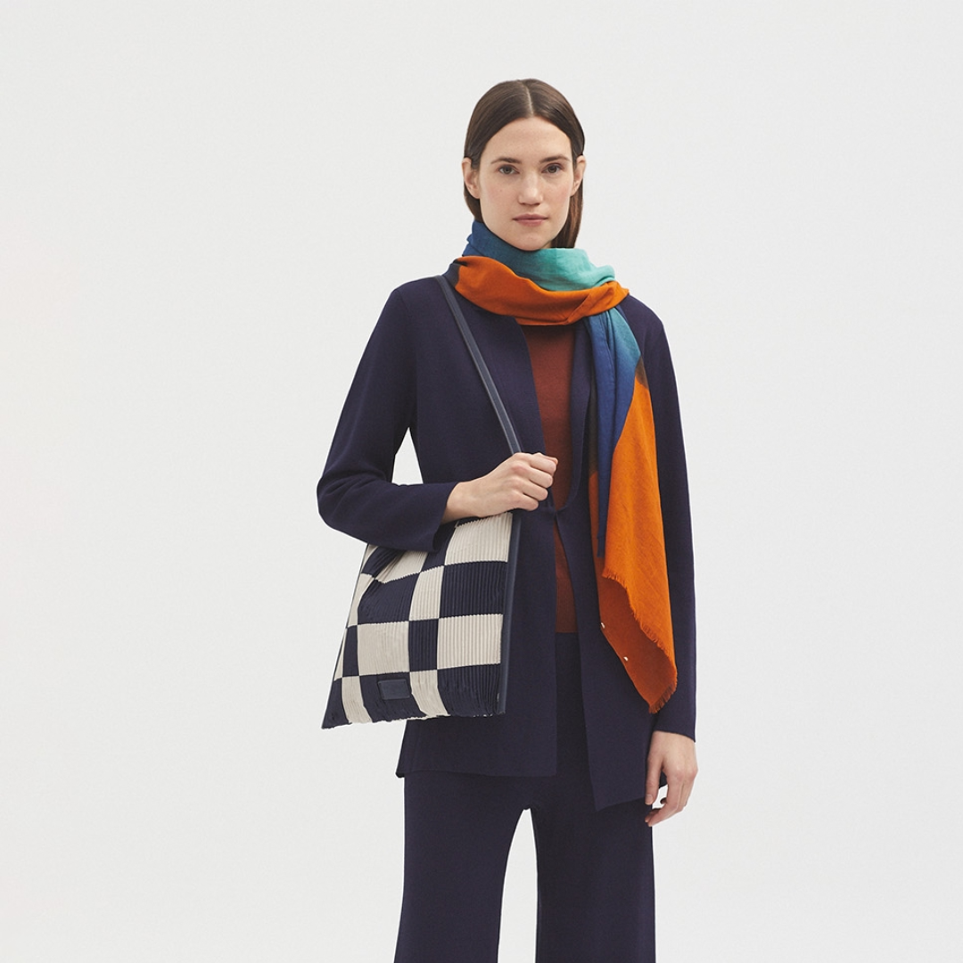 Checkered pleated tote bag with navy blue and off-white squares.  The bag has a navy blue leather-like trim.