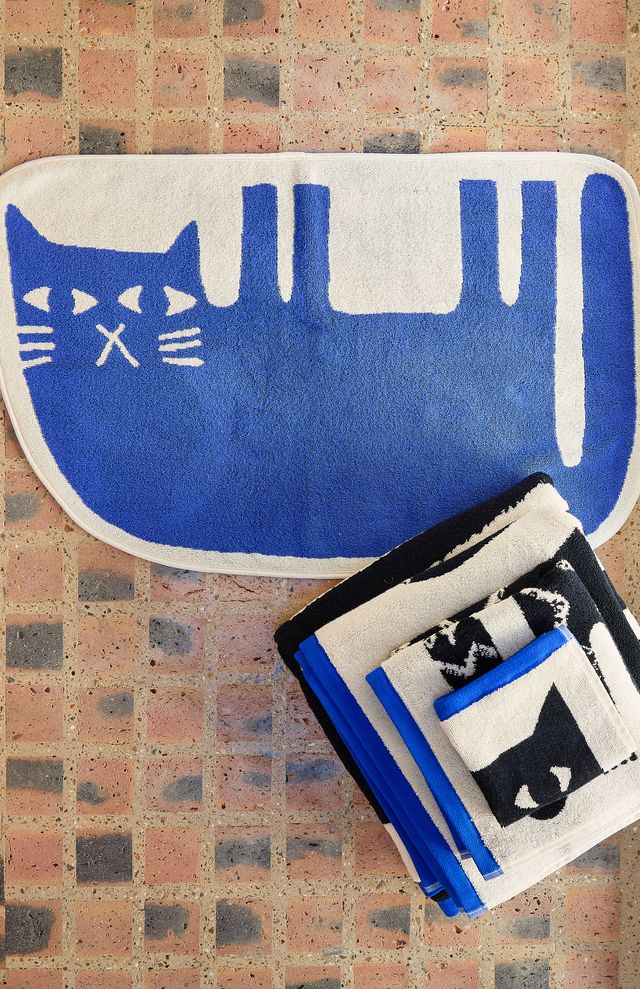 Blue and white cat-shaped rug on a brick floor