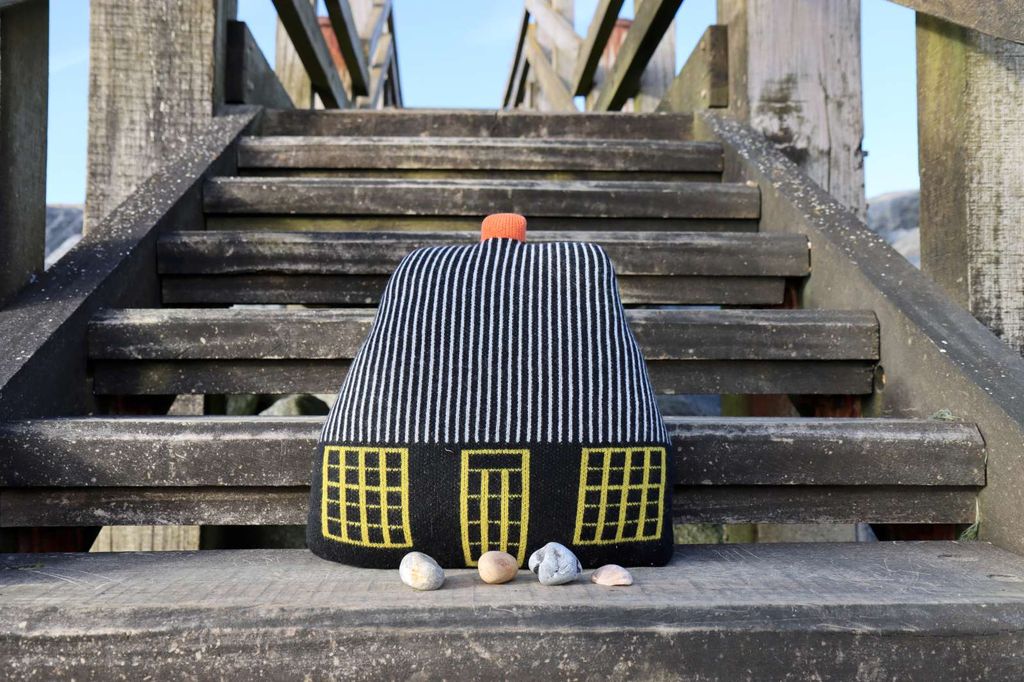 Striped fabric bag with a pom-pom on a wooden staircase