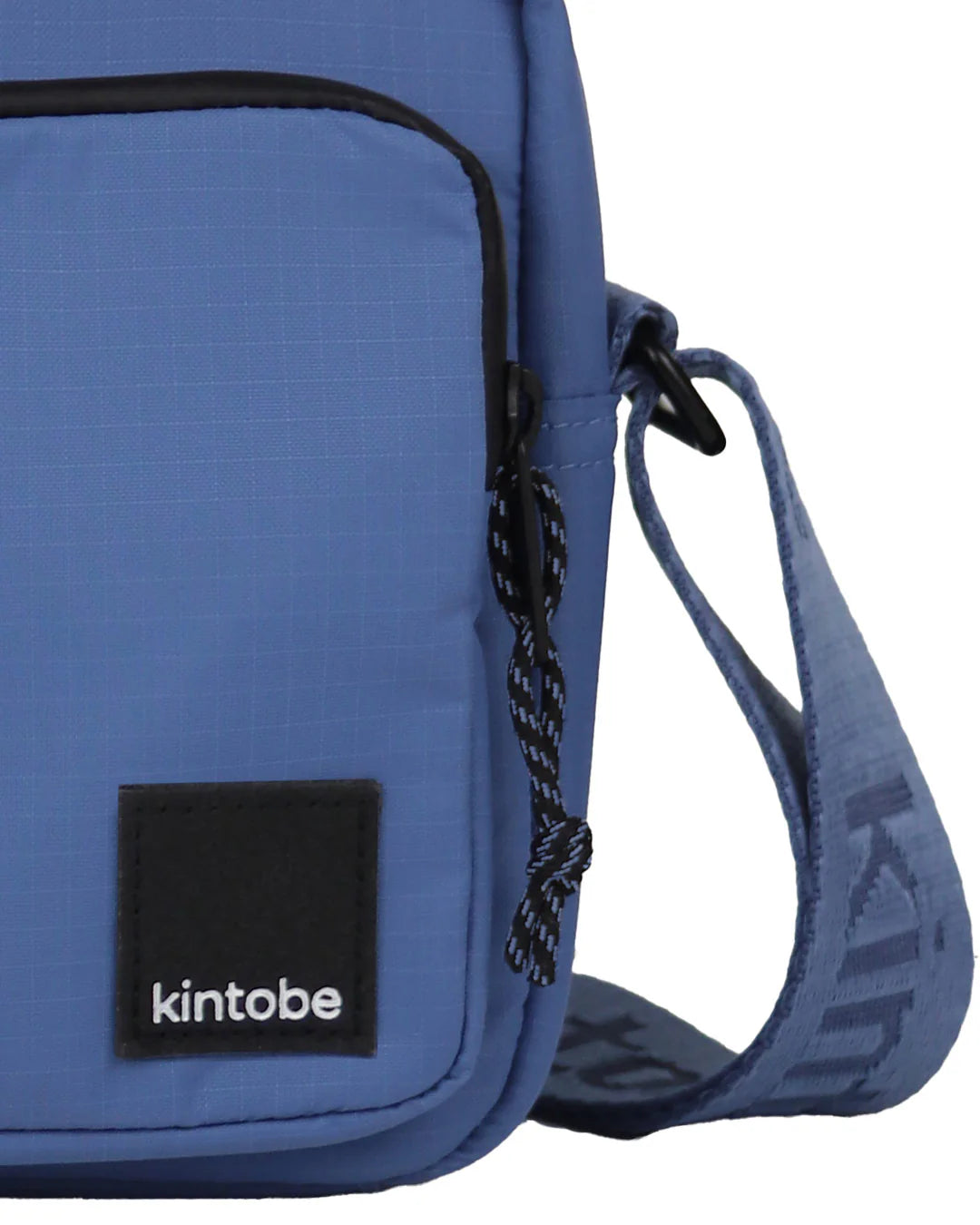 Blue Kintobe crossbody bag with black zipper, adjustable strap, and small black logo patch.