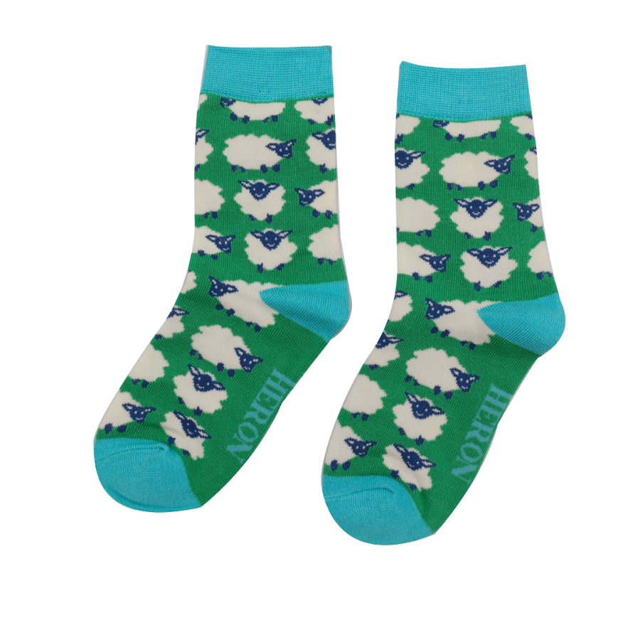 Pair of green crew socks with a repeating pattern of white sheep.  The socks have teal cuffs and a subtle logo.