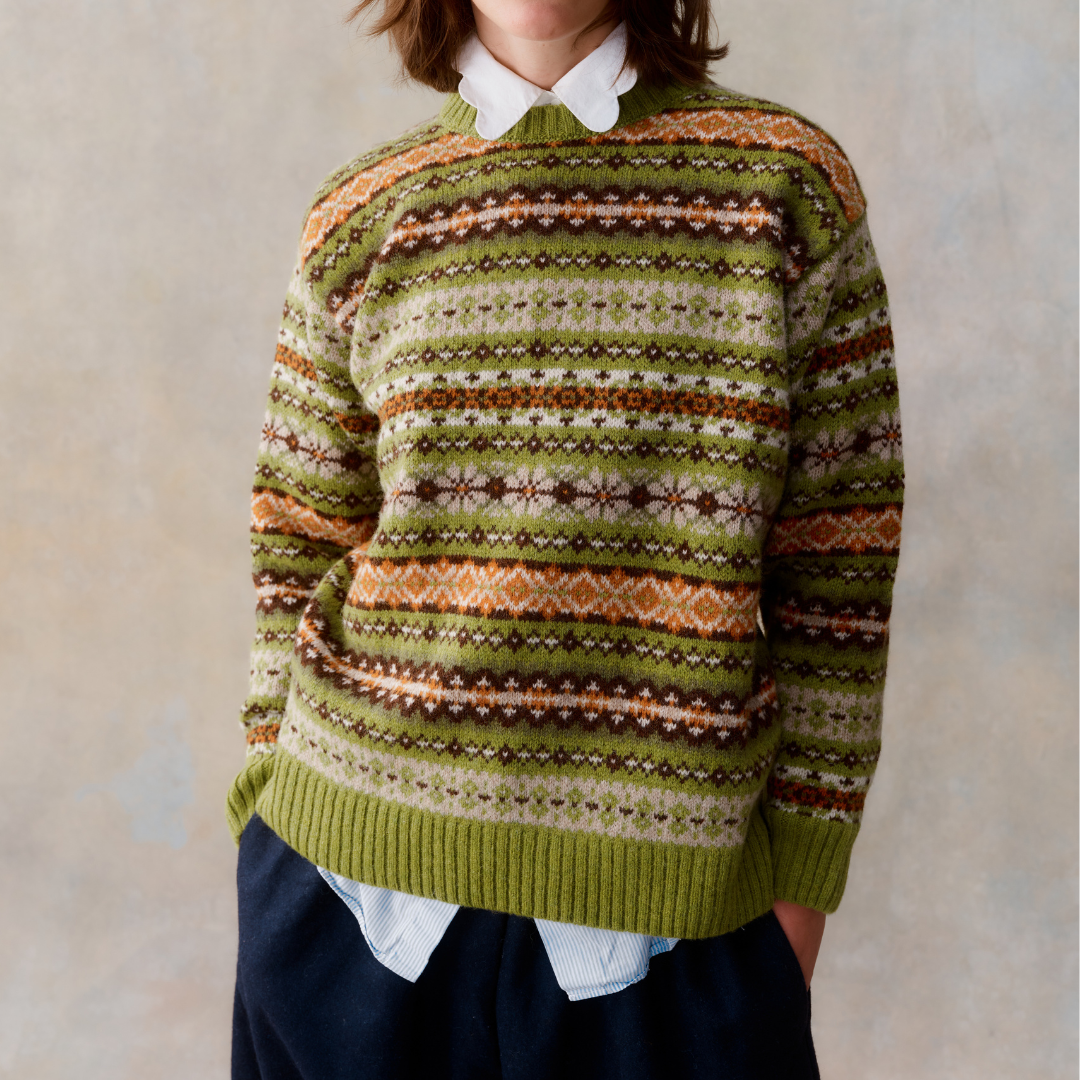 Fair isle knit sweater in olive green with brown, orange, and cream horizontal stripes and patterns.