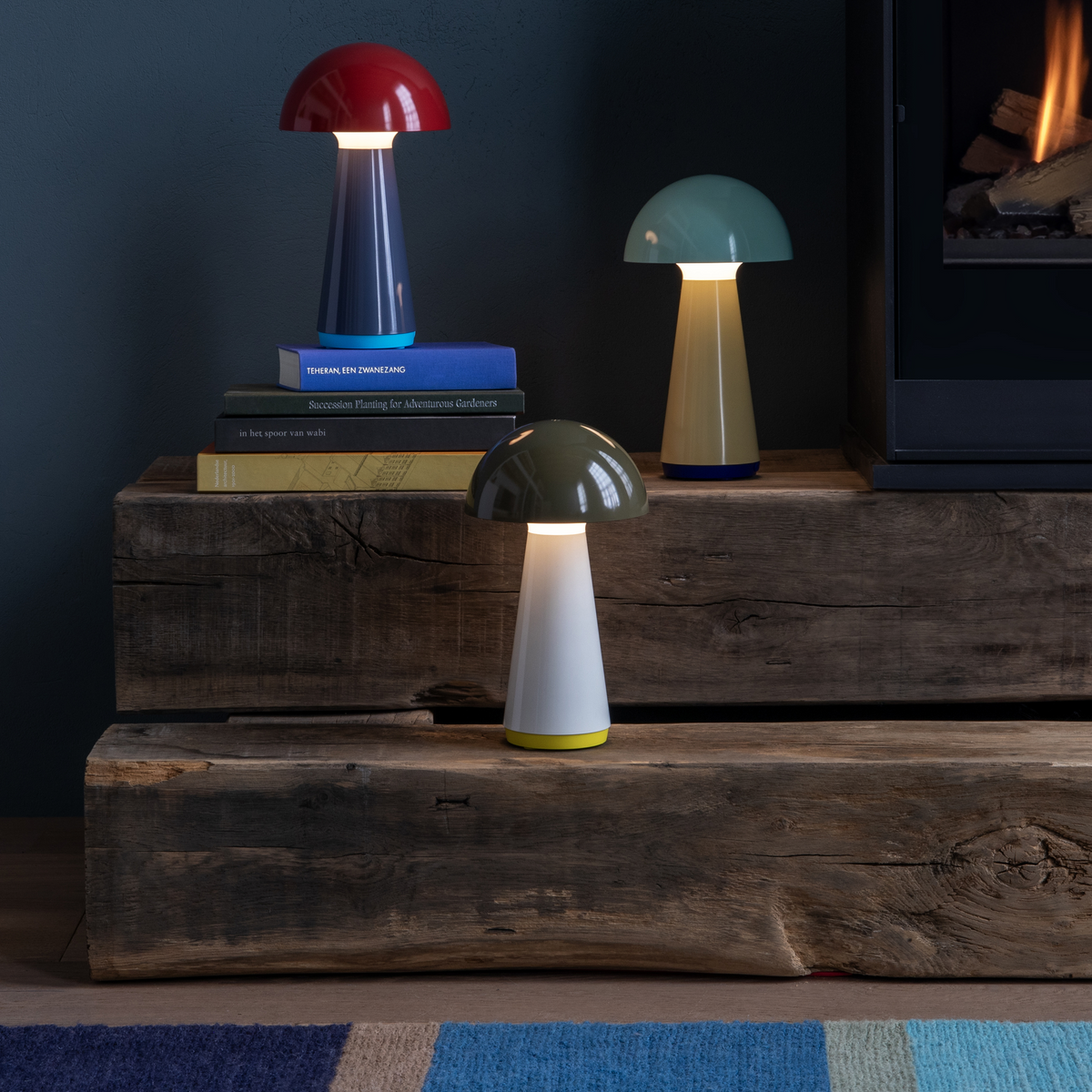 Three colorful mushroom-shaped lamps on a wooden surface with a dark wall background.