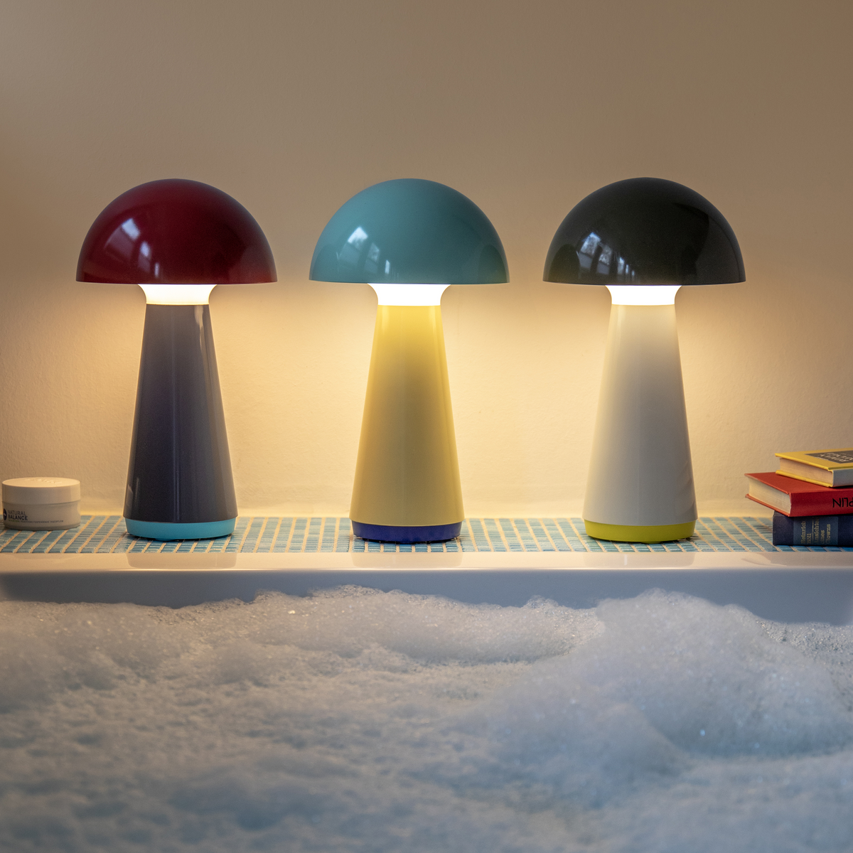 Three colorful mushroom-shaped lamps on a shelf with a soft, blurred background.