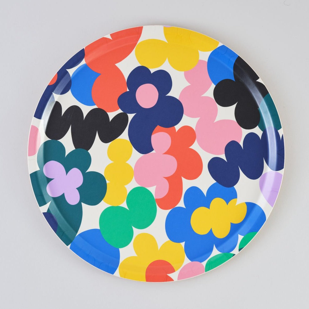 Round tray with a colorful, abstract floral pattern in shades of pink, blue, red, yellow, and green on a white background.