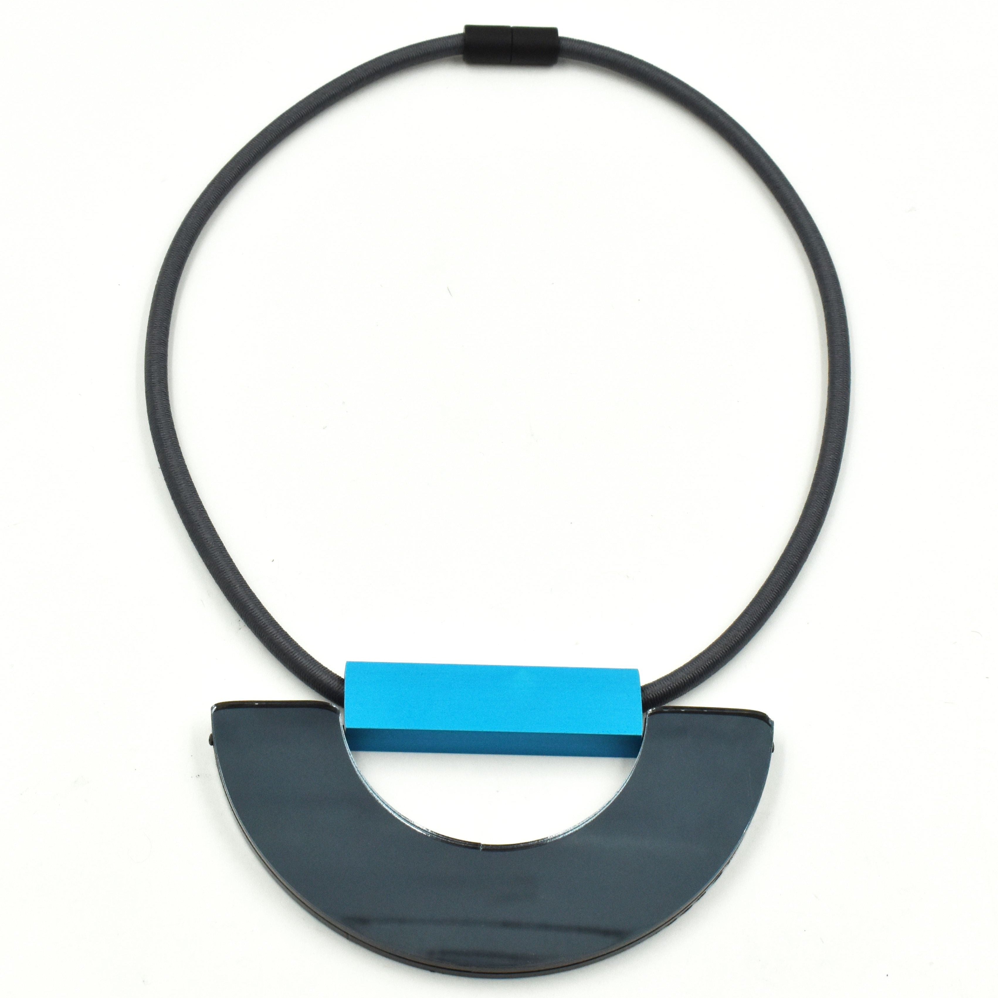 Gray elastic necklace with a dark gray semi-circular pendant and a bright blue rectangular accent piece.