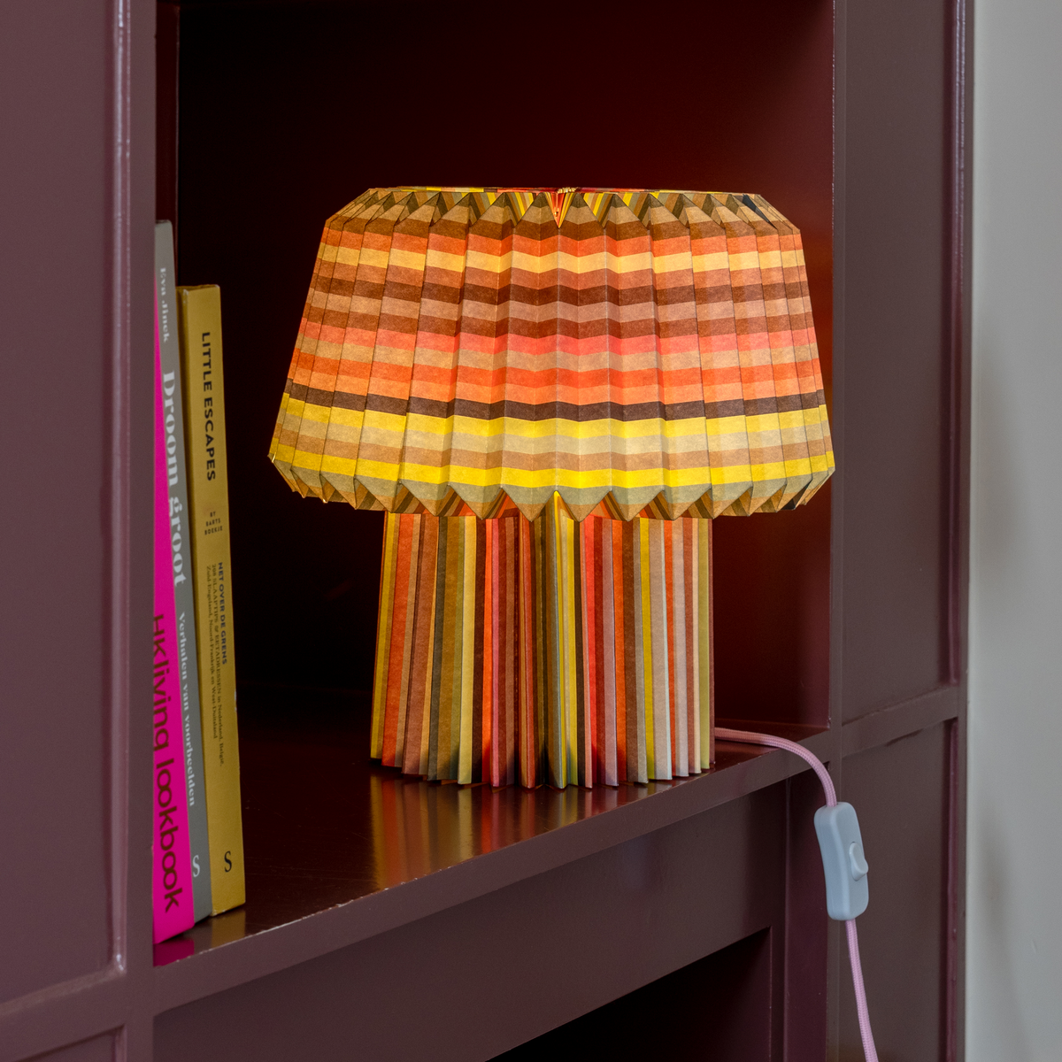 Colorful striped lamp on a shelf with books