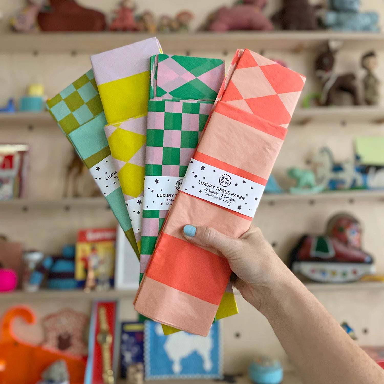 Hand holding a stack of colorful patterned luxury tissue paper.