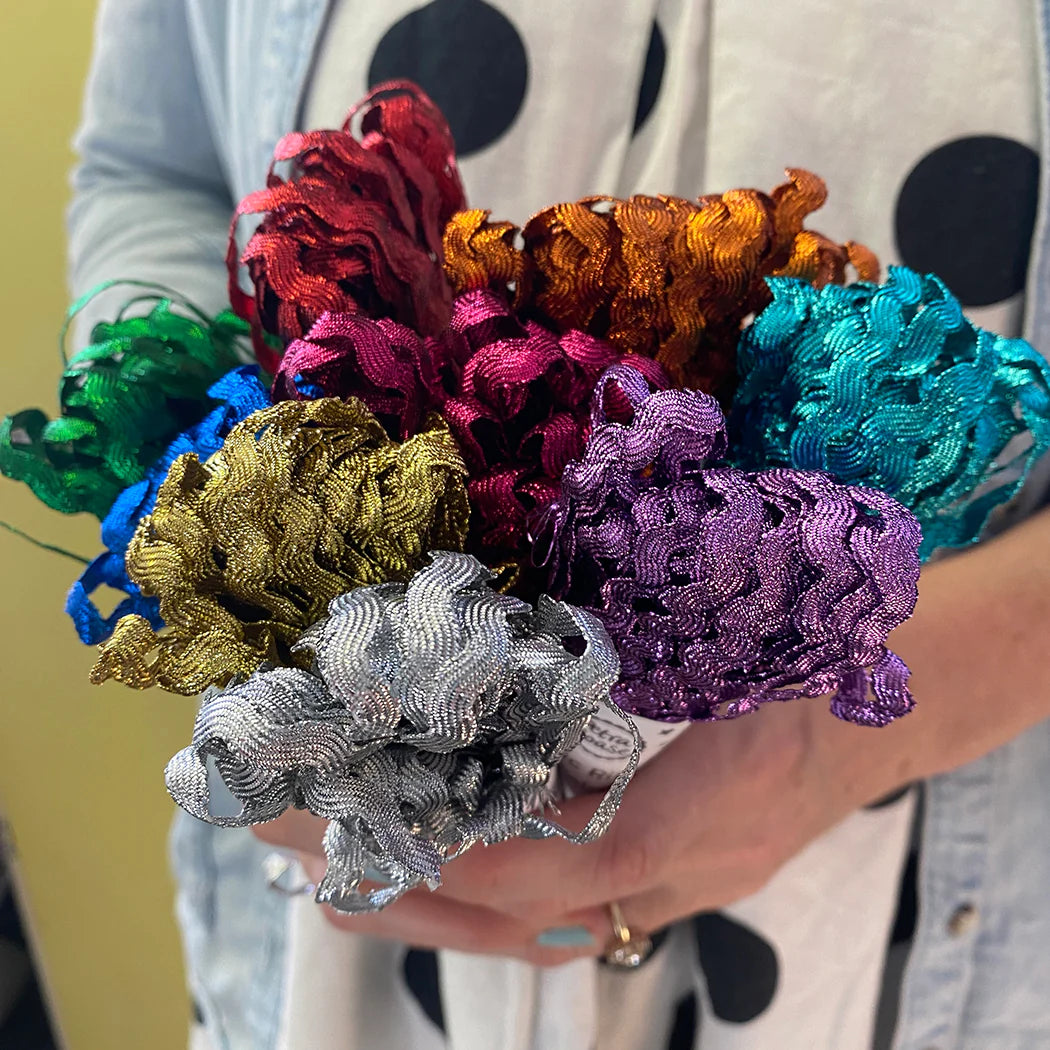 A bouquet of metallic, wavy ribbon in various colors, including red, orange, purple, teal, gold, and silver.
