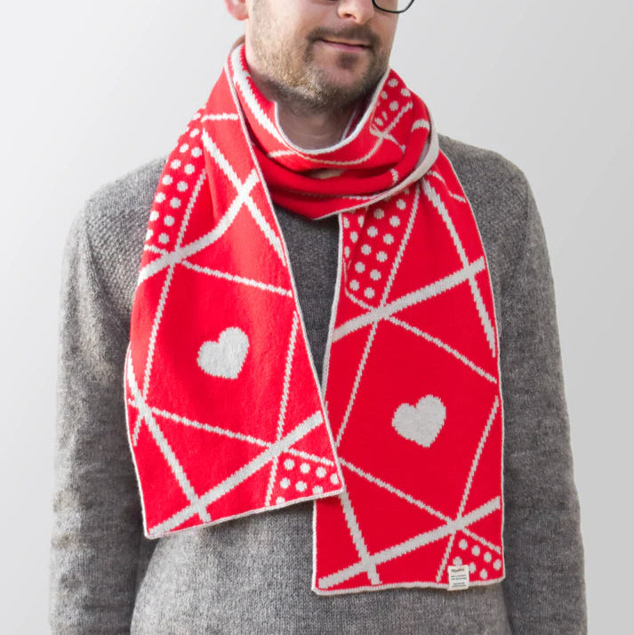 Red knitted scarf with a geometric pattern featuring white hearts and polka dots.
