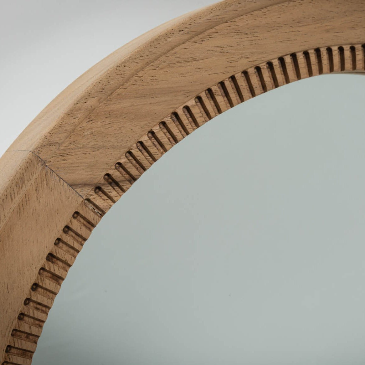 Round wood framed mirror with a detailed, textured edge.
