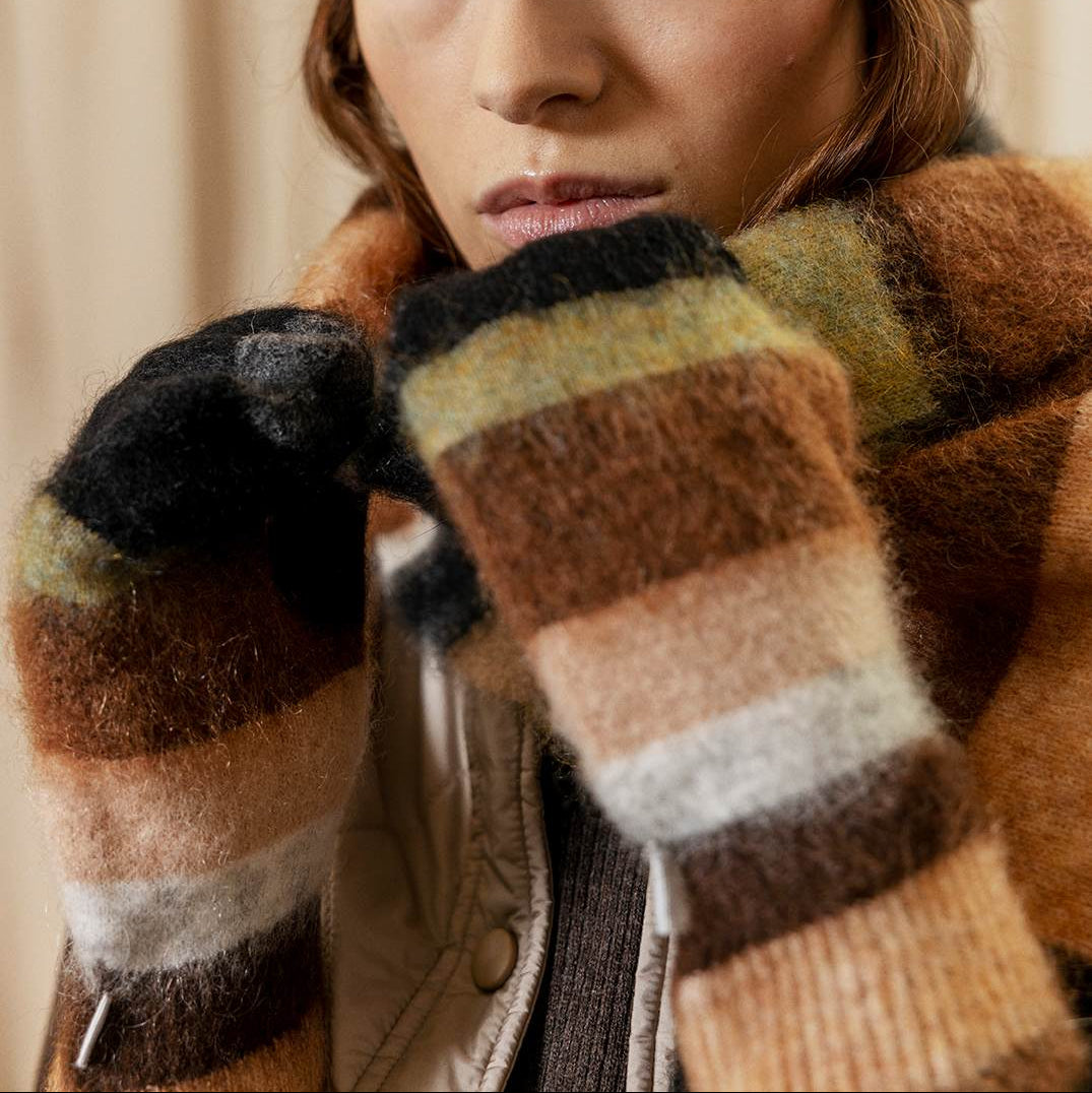 Person wearing a striped hat and gloves with a neutral background