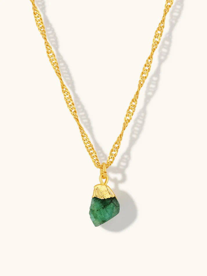 Gold necklace with a green pendant on a white background