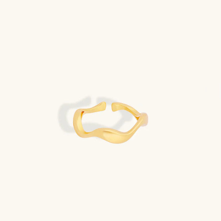 A gold-plated open ring band with a wavy, organic twist design, shown on a solid off-white background.