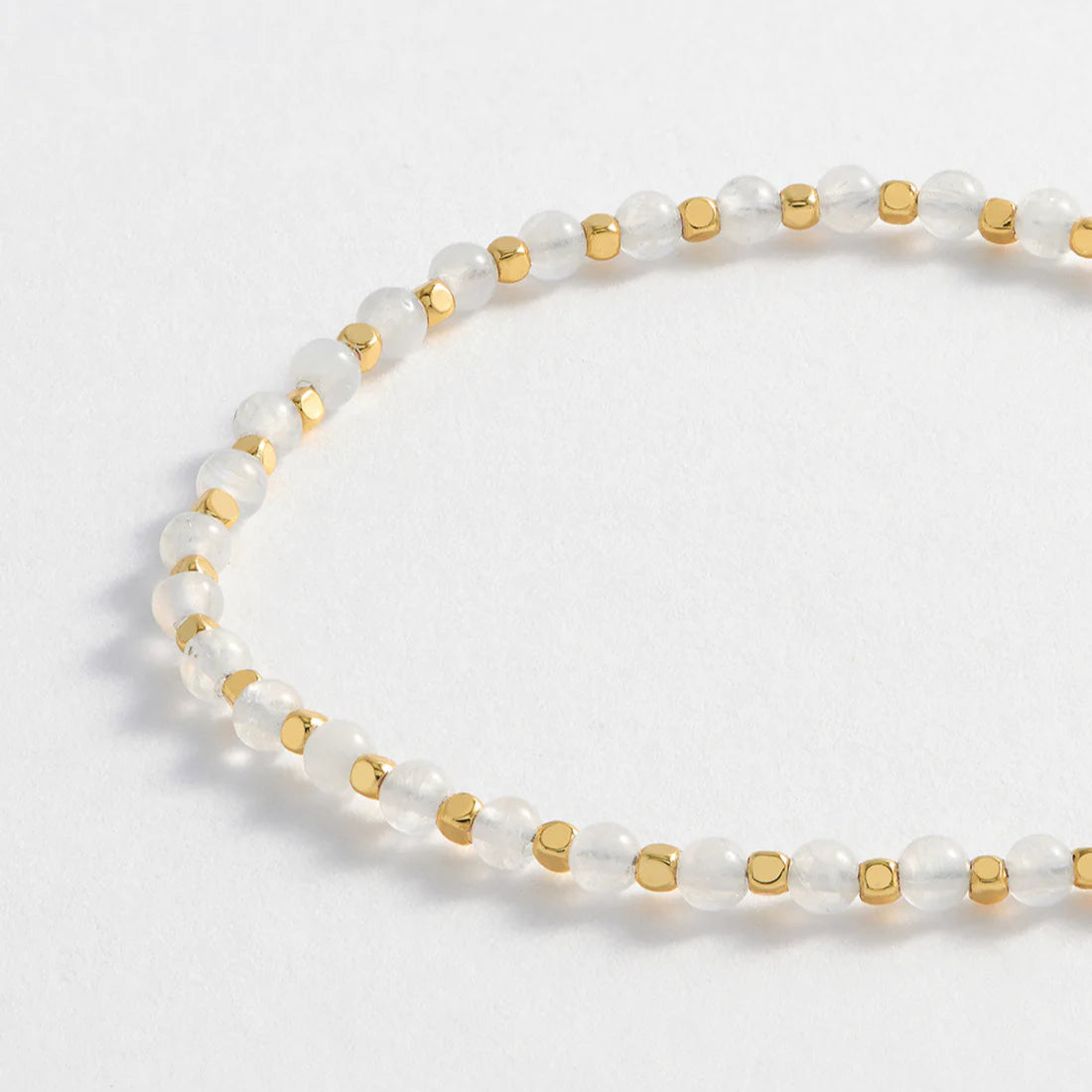 Delicate bracelet featuring alternating round white beads and gold cube beads.