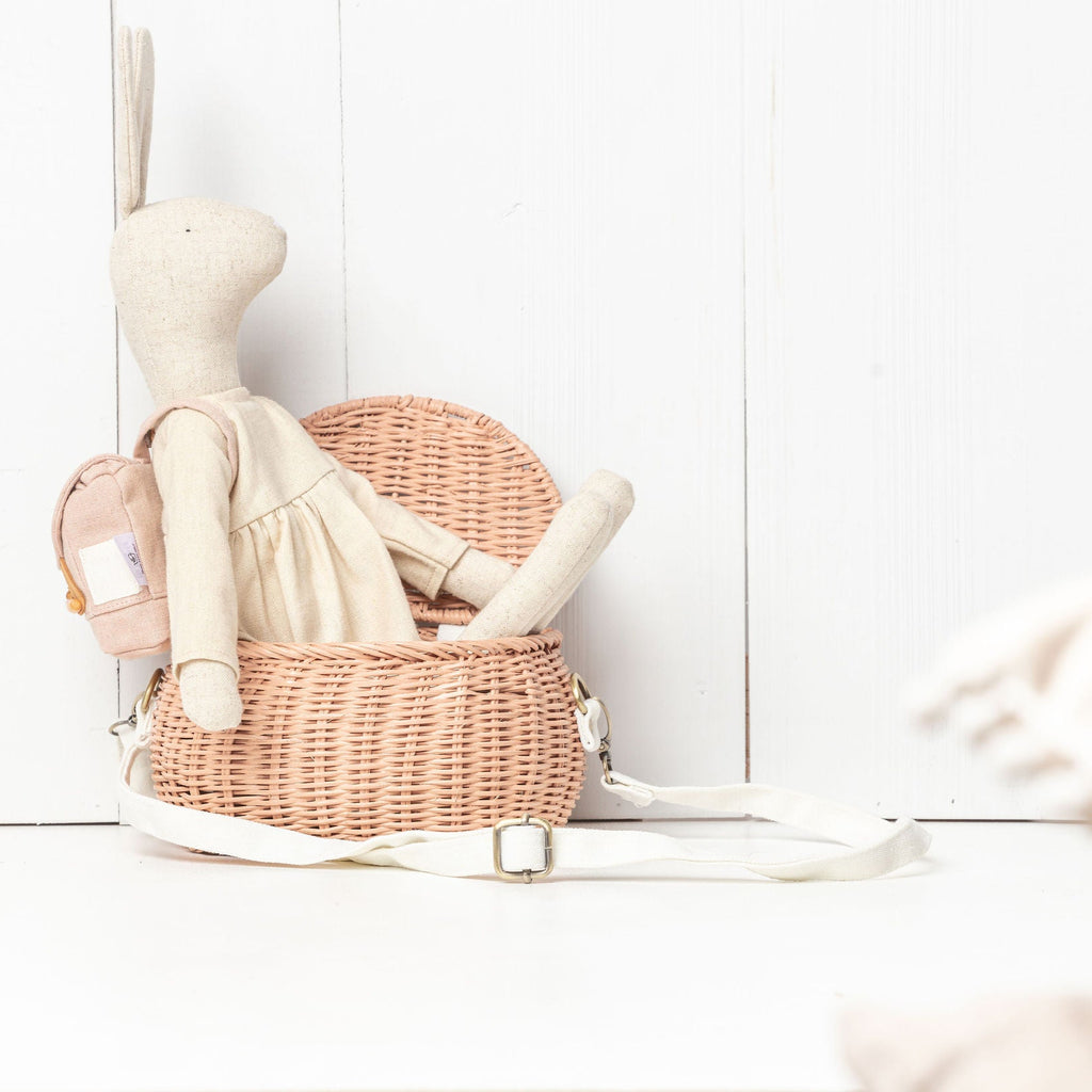 Stuffed rabbit toy with a pink wicker basket on a white surface